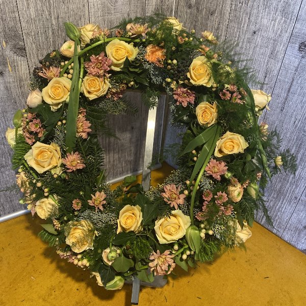 Trauerkranz rundgesteckt mit orangenen Rosen, passenden Blumen und Grün Bild 1
