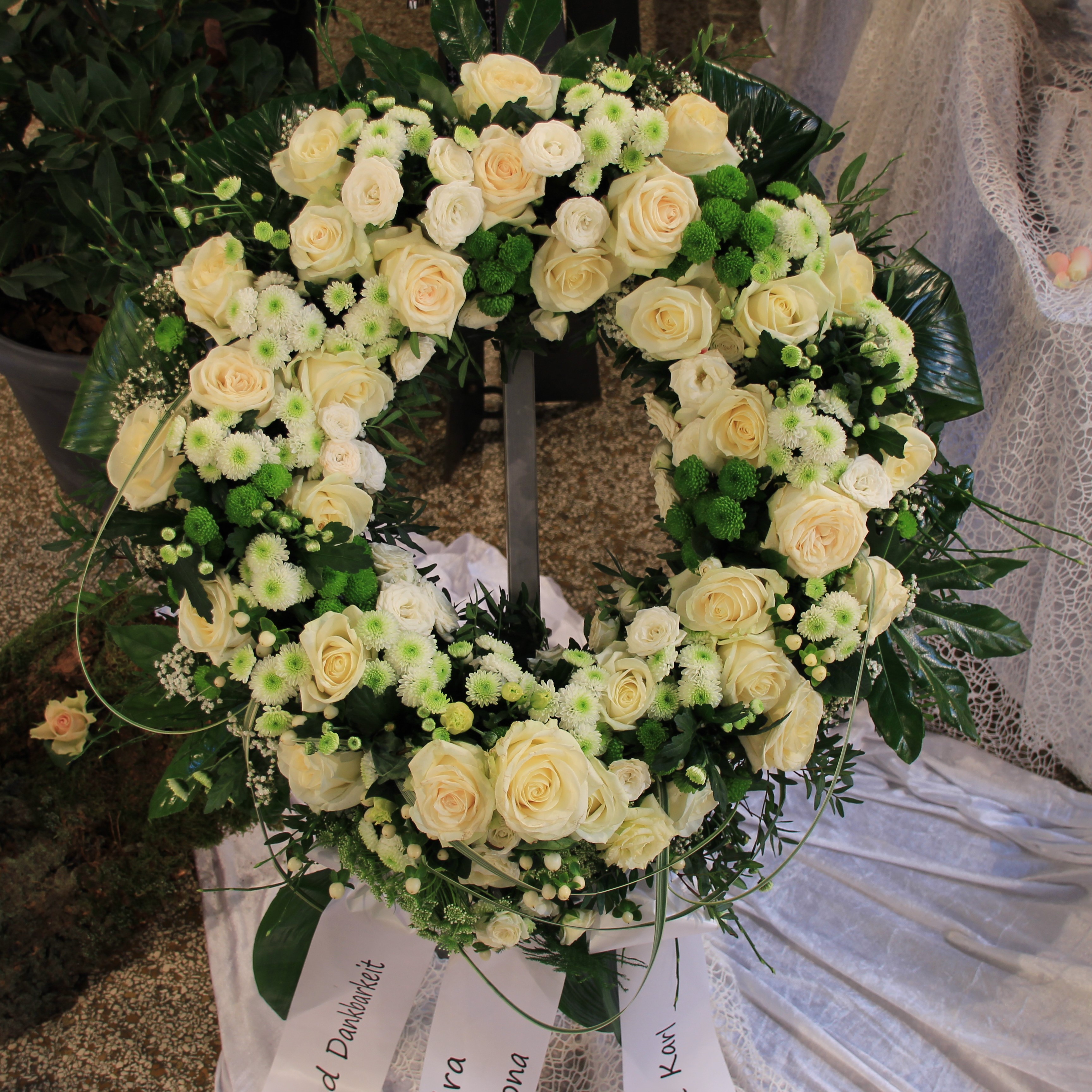 Trauerkranz rundgesteckt mit weißen Rosen, weißen Blumen und Grün Bild 1